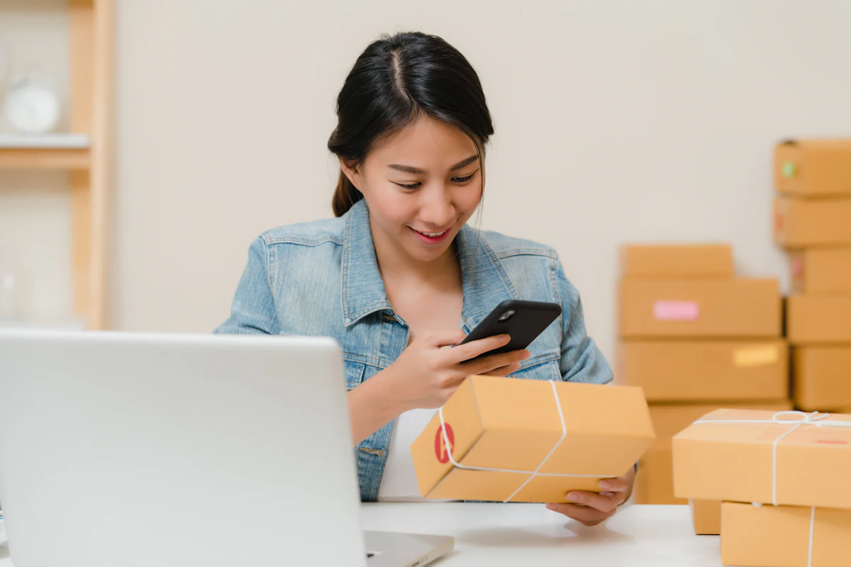 Store owner checking an order on her phone next to packed parcels